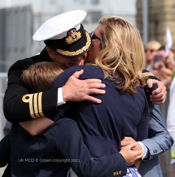 Navy officer hugging family